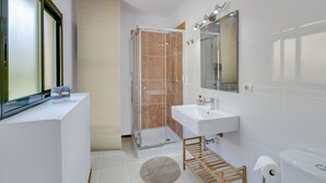 A modern bathroom with a glass-enclosed shower, a white sink, and a large mirror.