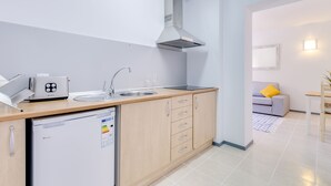 A compact kitchen with a dishwasher, a toaster, a sink, and a stainless steel range hood.