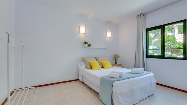 A bedroom with a bed, bedside tables, a window, and a towel rack.