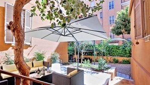 An outdoor patio with wicker furniture, a white umbrella, and a tree trunk. - MONTEVERDE GUESTHOUSE: Spacious Villa in Rome Center ! (Roma)