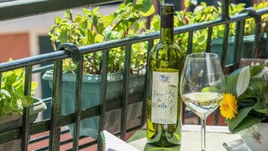 A bottle of wine, a glass of white wine, and a notebook on a table outdoors. - Recanissu Apartment with Balcony & AC (Vernazza)