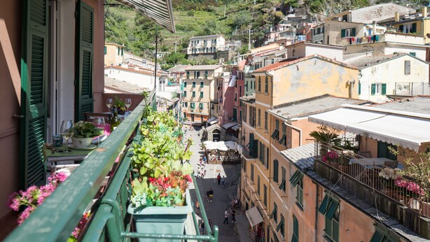 A balcony with potted plants and a table with wine glasses. - Recanissu Apartment with Balcony & AC (Vernazza)