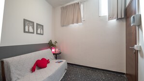 A small room with a bed, a small table with a plant, and a wall with two framed pictures. - Recanissu Apartment with Balcony & AC (Vernazza)