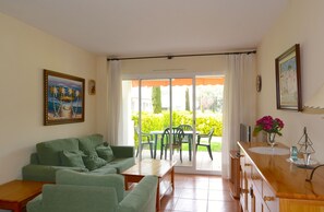 Relax in this open-plan living area with a sofa set, coffee table, and sliding door to an outdoor patio.