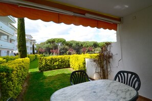 Relax in a serene outdoor space with a table and chairs, surrounded by lush greenery and a residential view.