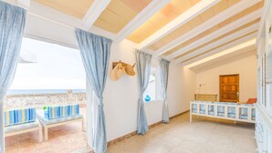 Ein Zimmer mit Balkon, Holzboden und einer Sitzbank mit Kissen.