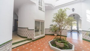 A spacious interior with a tiled floor, a central planter with greenery, and a door leading to another room. - Cubo's Apartamento Tarajes La Cala / free wifi / air conditioning (Mijas Costa)