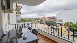 A balcony with a table and chairs, a view of the street, and a building with a sign. - Cubo's Apartamento Tarajes La Cala / free wifi / air conditioning (Mijas Costa)