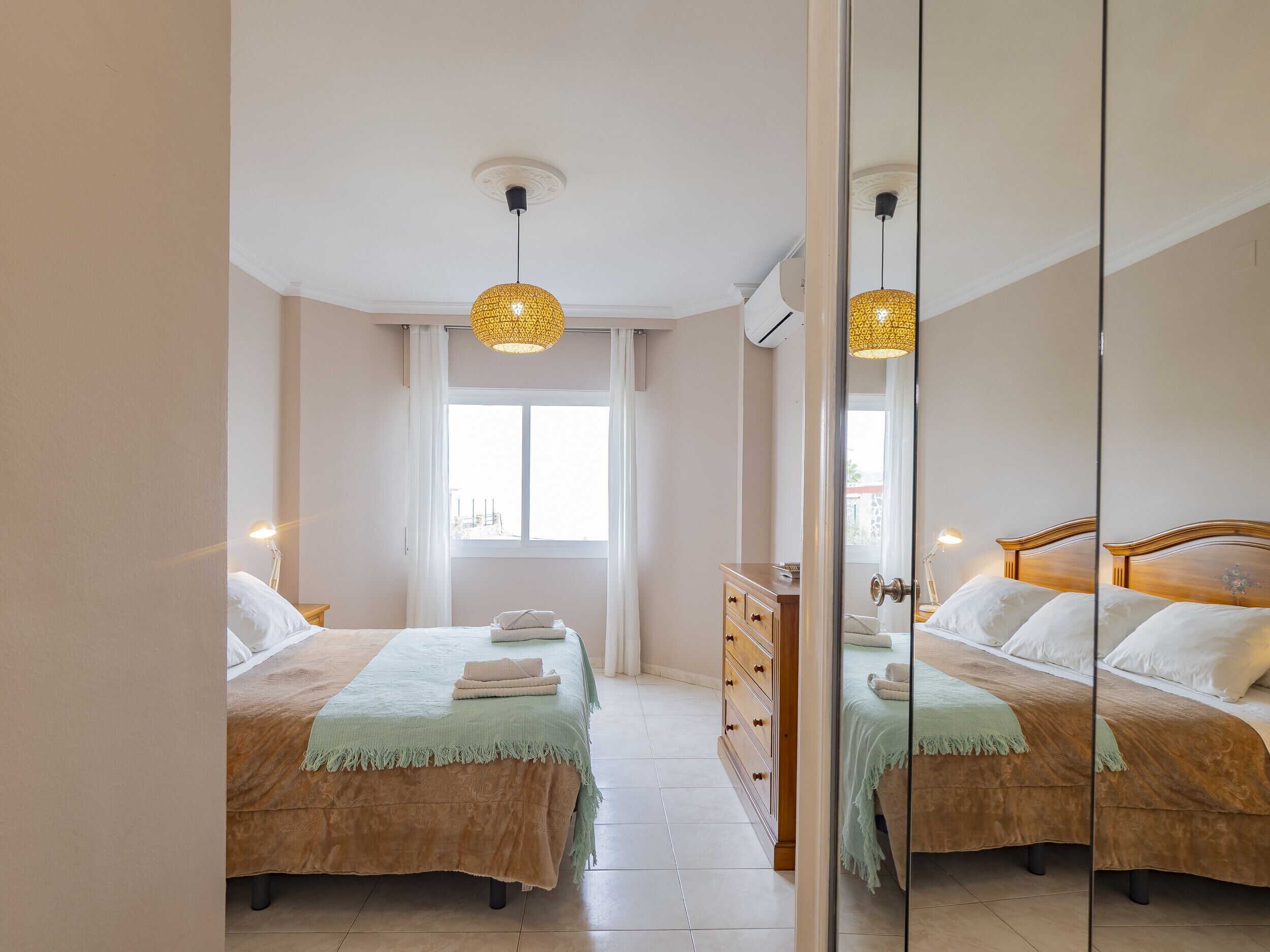 Une chambre avec deux lits, une commode et un grand miroir.