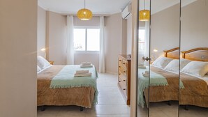 A bedroom with two beds, a dresser, and a large mirror. - Cubo's Apartamento Tarajes La Cala / free wifi / air conditioning (Mijas Costa)