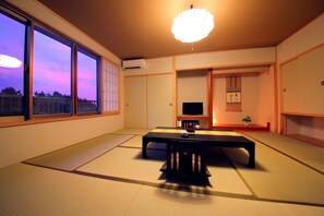 A traditional Japanese room with tatami flooring, a low table, and a television. - Kuju Kanko Hotel (Kokonoe)