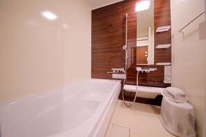 Een aparte badkuip en douche, pantoffels, handdoeken