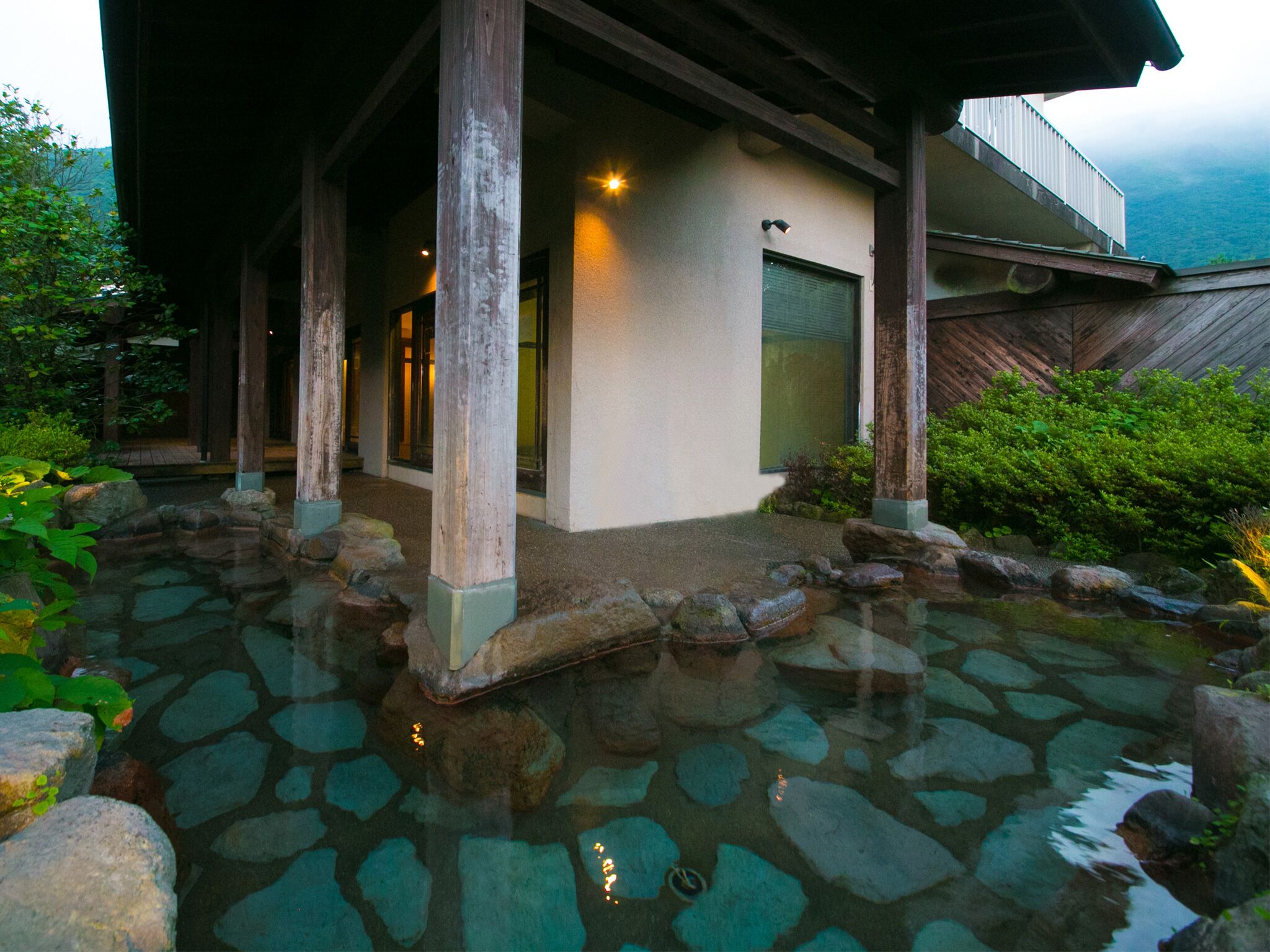 A traditional Japanese building with a stone water feature in front.