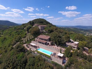 A villa with a swimming pool, surrounded by lush greenery and hills.