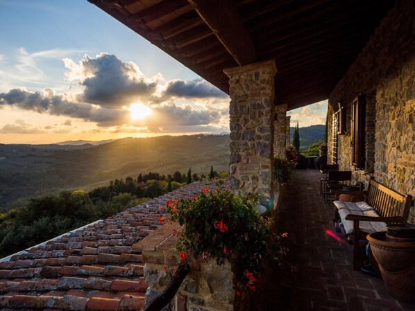 Um edifício de pedra com terraço e vista para uma paisagem montanhosa.