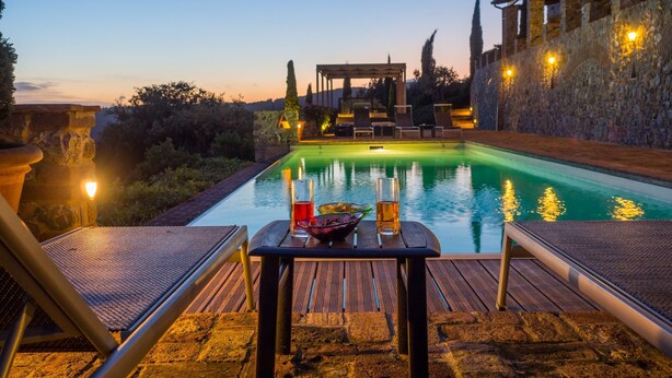 A poolside area with a table and chairs, a stone wall, and a view of the pool. - the best location in the Maremma for maremmaguide (pari)