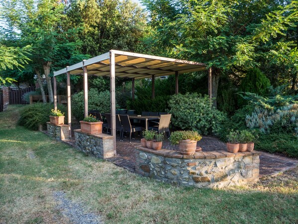 Un espacio al aire libre techado con paredes de piedra y plantas en macetas.
