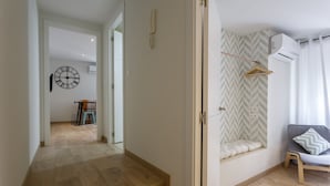 A modern interior with a wooden floor, a built-in bench with a hanging coat rack, and a grey sofa with a pillow. - La Herencia del REGIDOR by Cadiz4Rentals (Cádiz)