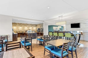 Relax in a stylish dining area with a large flat-screen TV, comfortable seating, and a variety of tables.