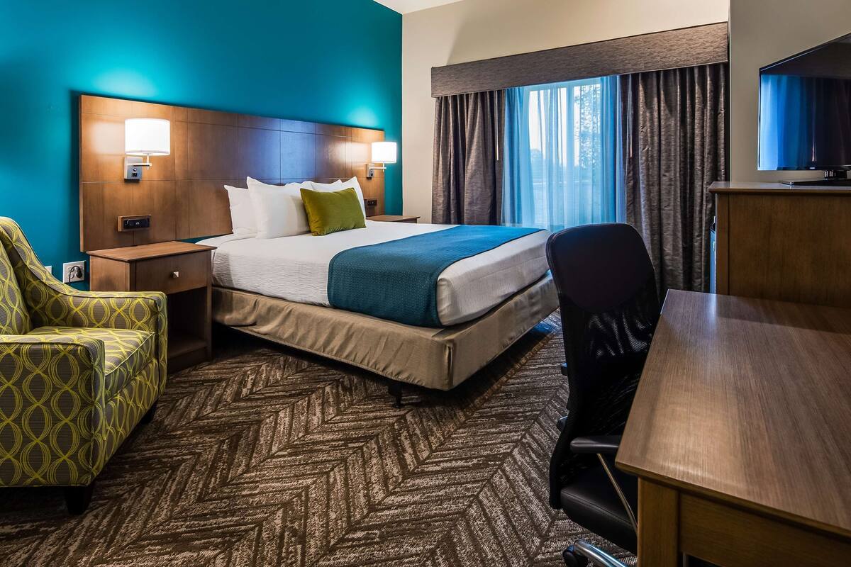 A hotel room with a bed, a desk, a chair, and a nightstand.