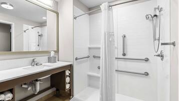 Un baño moderno con ducha, lavamanos y espejo.