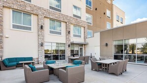 An outdoor patio area with wicker furniture, a glass-top table, and a stone wall. - Best Western Plus Bolivar Hotel & Suites (Bolivar)