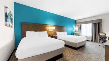 Habitació d'hotel amb dos llits, una tauleta de nit, un escriptori i una finestra amb cortines.
