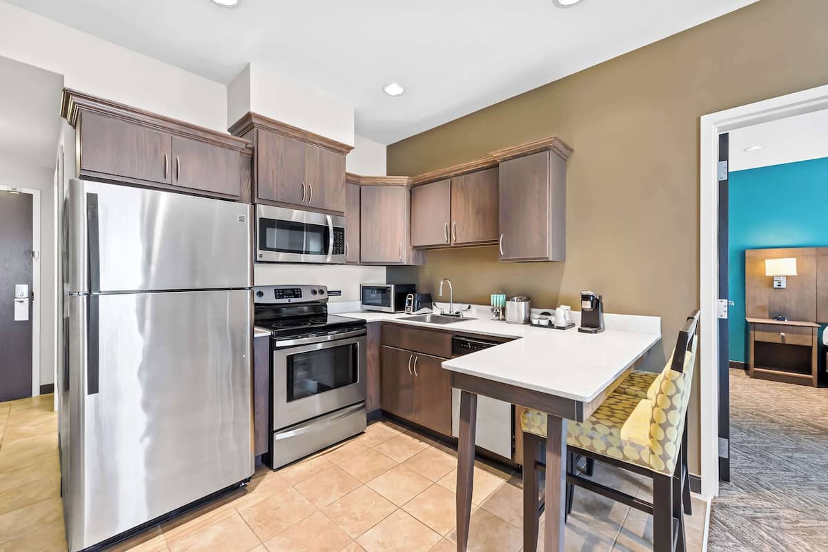 A modern kitchen with stainless steel appliances, wooden cabinets, and a white countertop.