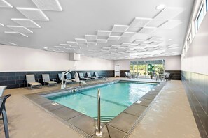 Relax by the pool surrounded by lounge chairs and a safety railing.