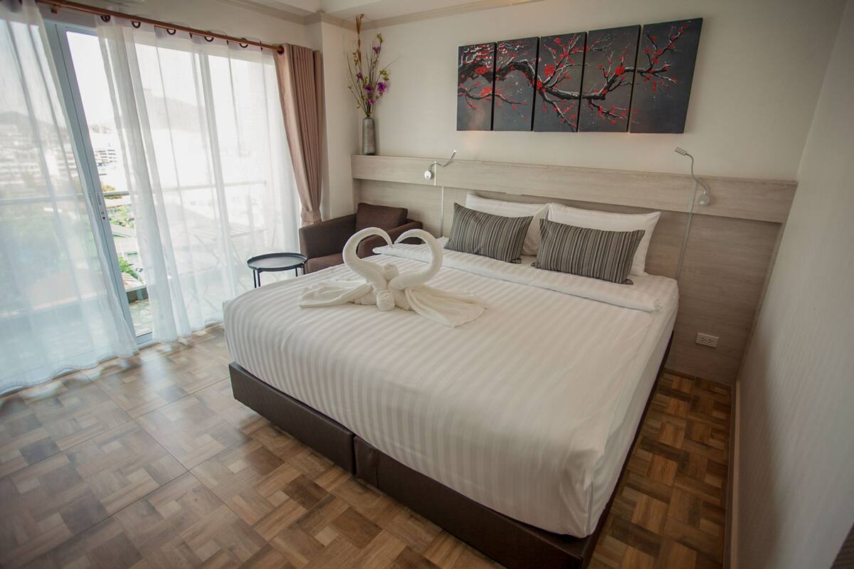 A modern hotel room with a large bed, a desk, and a view of the outdoors.