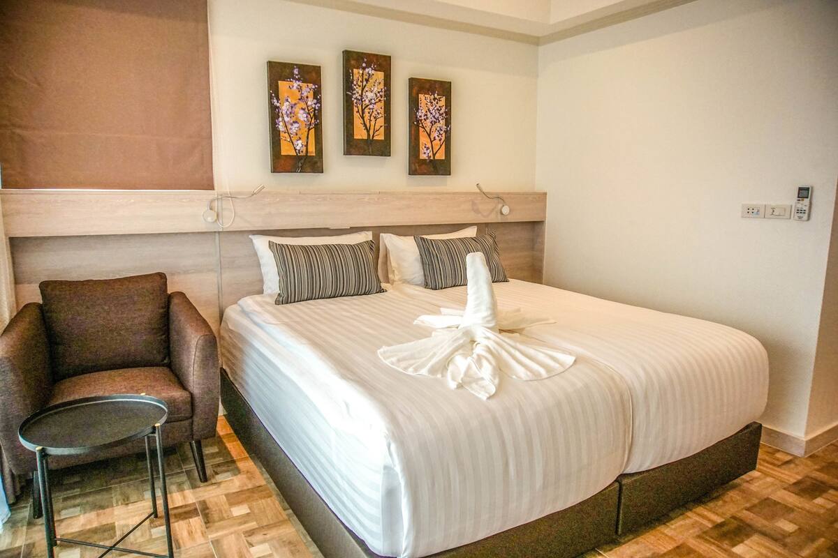 A hotel room with a large bed, a chair, and three wall-mounted paintings.