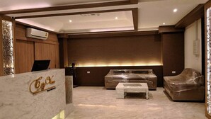 A modern lobby with a reception desk, seating area, and a large window with blinds. - Cityview Residence (Si Racha)