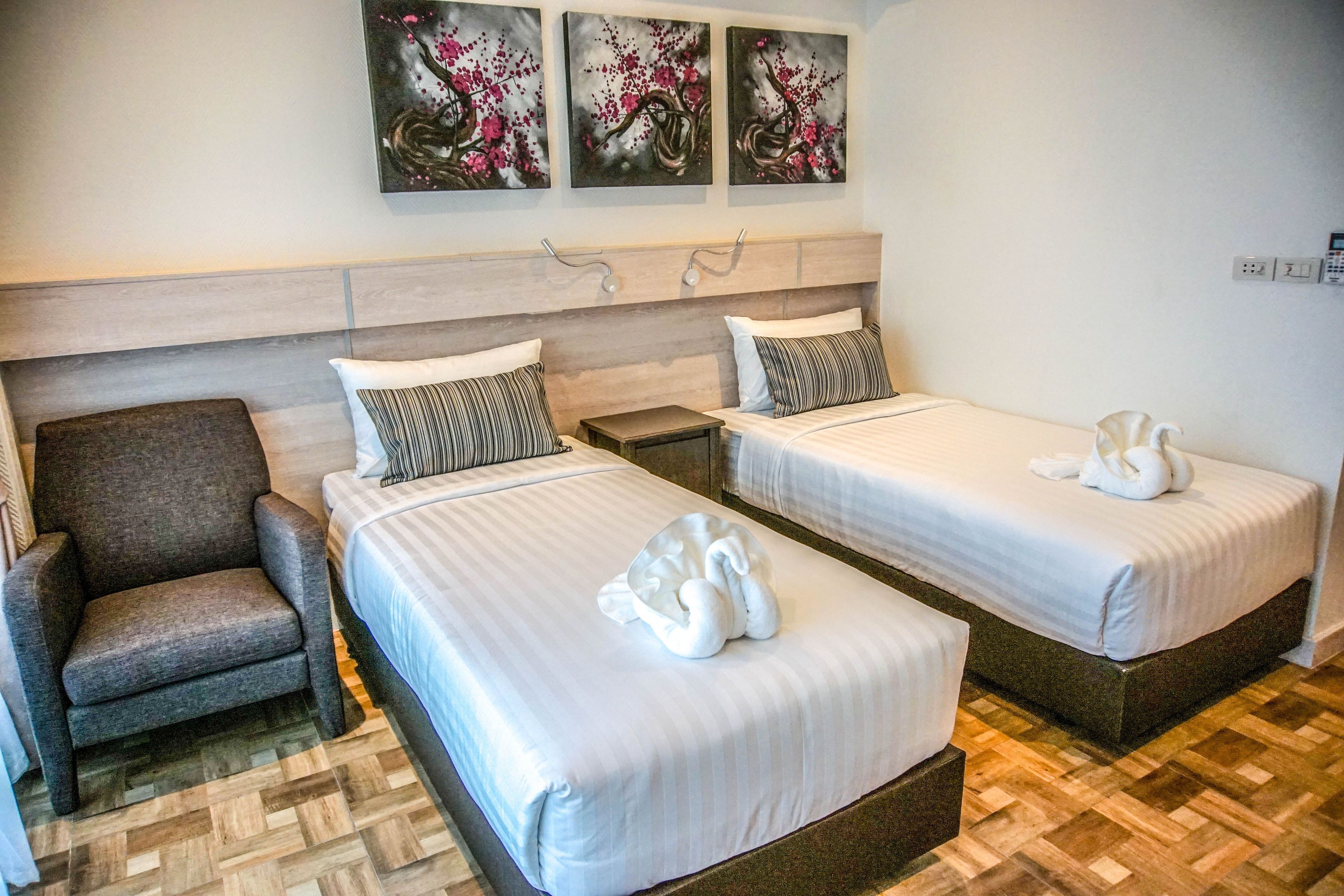 Habitación de hotel con dos camas, una silla y una obra de arte en la pared.