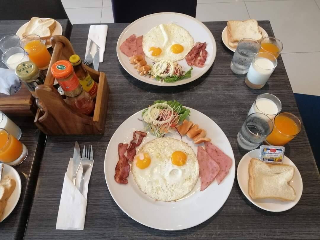 A breakfast setting with plates of eggs, bacon, and toast, along with condiments and orange juice.