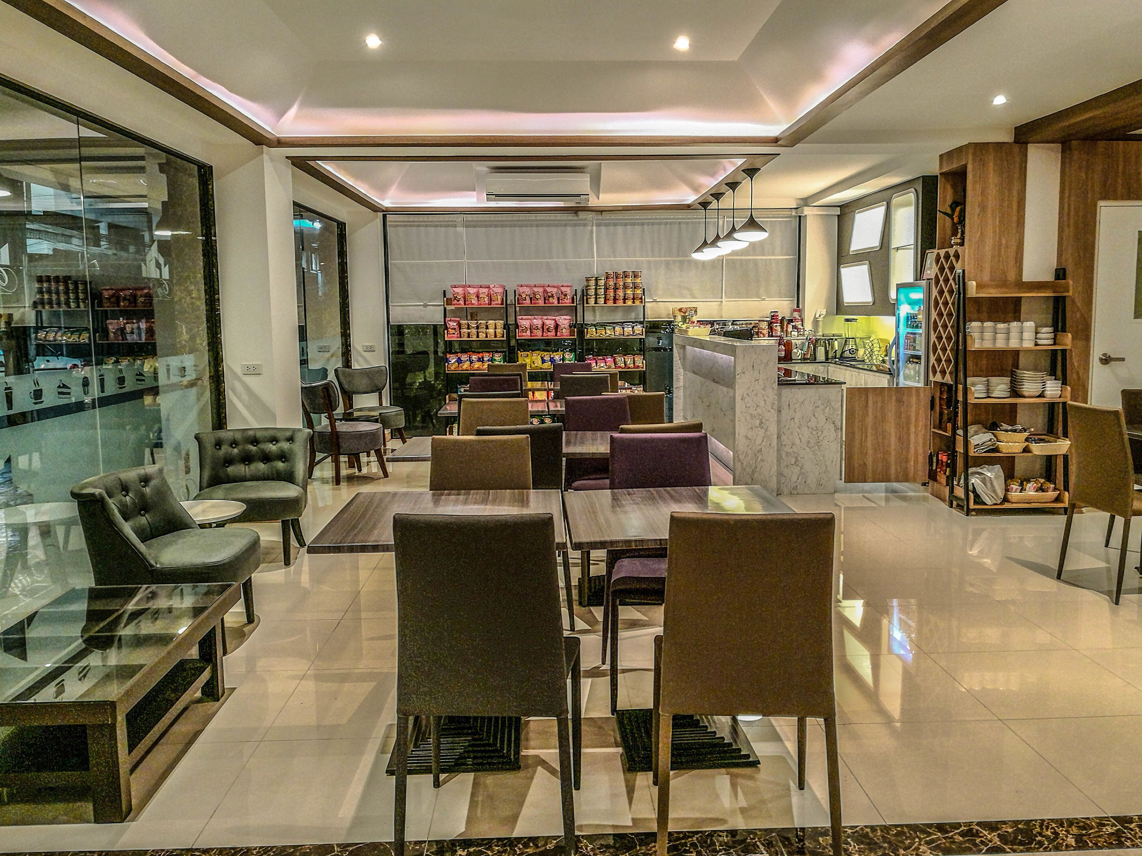 A modern restaurant with glass partitions, cushioned seating, and a variety of food items on display.