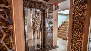 A modern interior with a glass door, marble walls, and a staircase. - Cityview Residence (Si Racha)