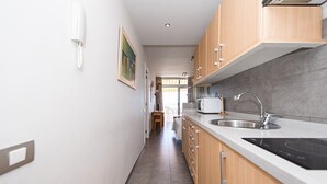 A modern kitchen with wooden cabinets, a stainless steel sink, and a built-in microwave.