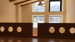 A room with a wooden bench, a ceiling fan, and large windows with a snowy landscape view. - Lodge Nakajima (Nozawaonsen)