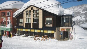 A building with a snow-covered roof and multiple windows, surrounded by snow. - Lodge Nakajima (Nozawaonsen)