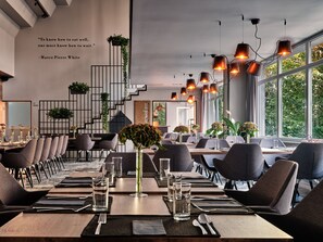 Un restaurante moderno con una larga mesa de comedor, múltiples sillas y lámparas colgantes.