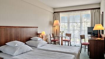 Une chambre d’hôtel avec deux lits, un bureau avec une télévision et un coin repas comprenant des chaises et une table.