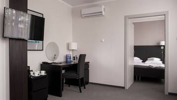 Ein Hotelzimmer mit Schreibtisch, Stuhl, Bett und einem an der Wand befestigten Fernseher.