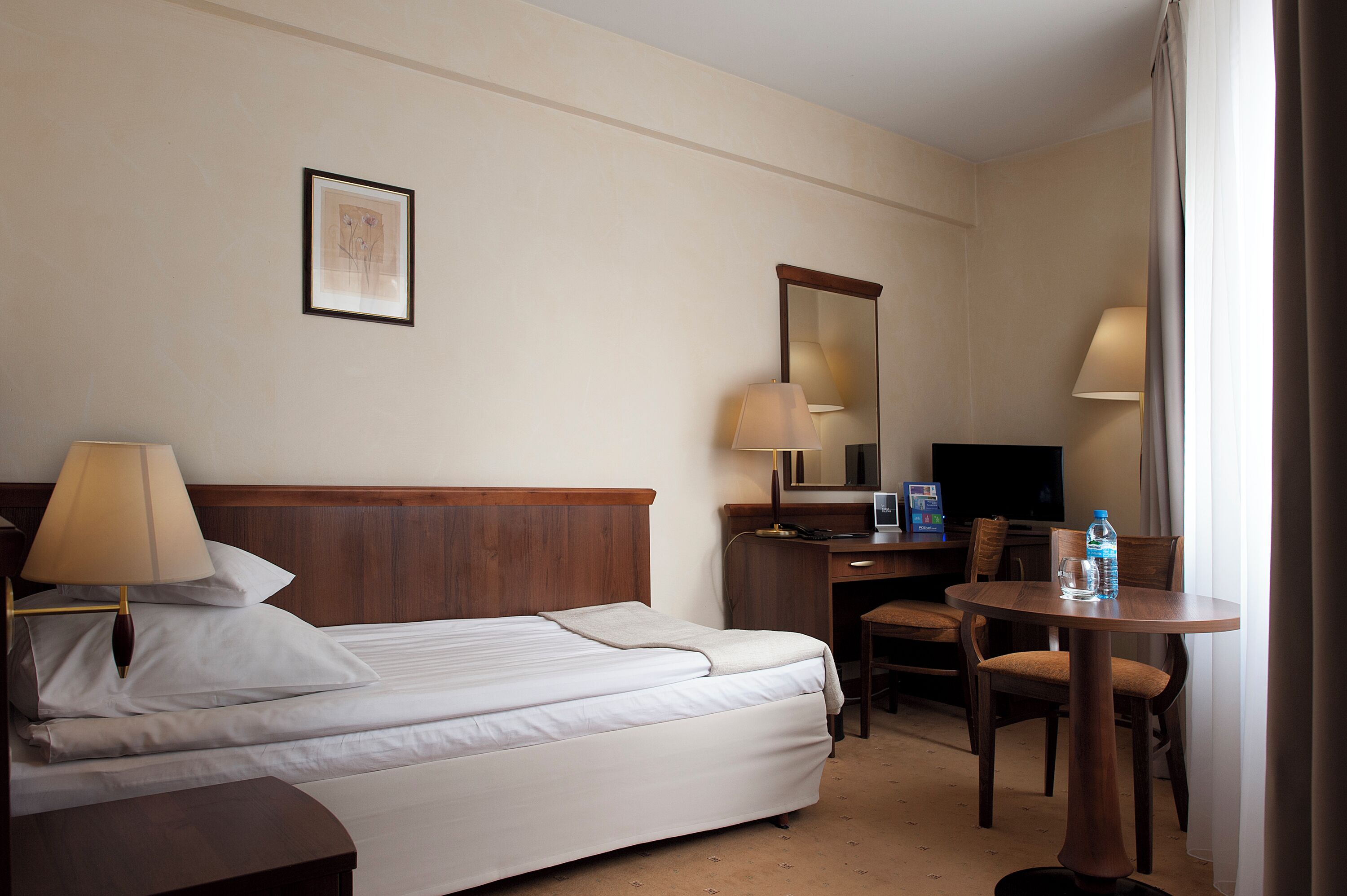 Une chambre d’hôtel équipée d’un lit, d’un bureau, d’une chaise, d’une télévision et d’une lampe.