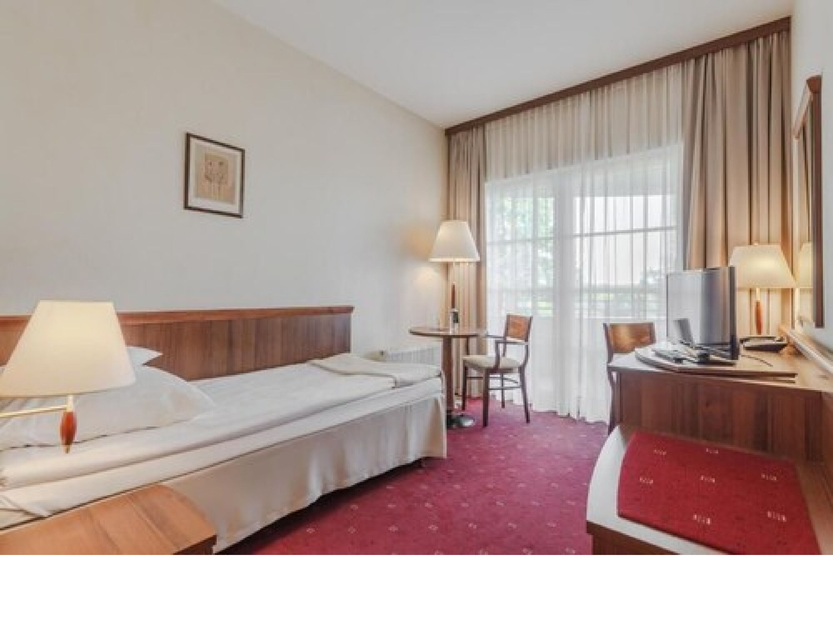 A hotel room with a single bed, a desk with a chair, a television, and a window with curtains.