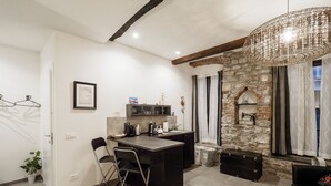 A modern kitchen with a central island, a stone accent wall, and a hanging light fixture. - Camaella Luxury Studio (Vernazza)