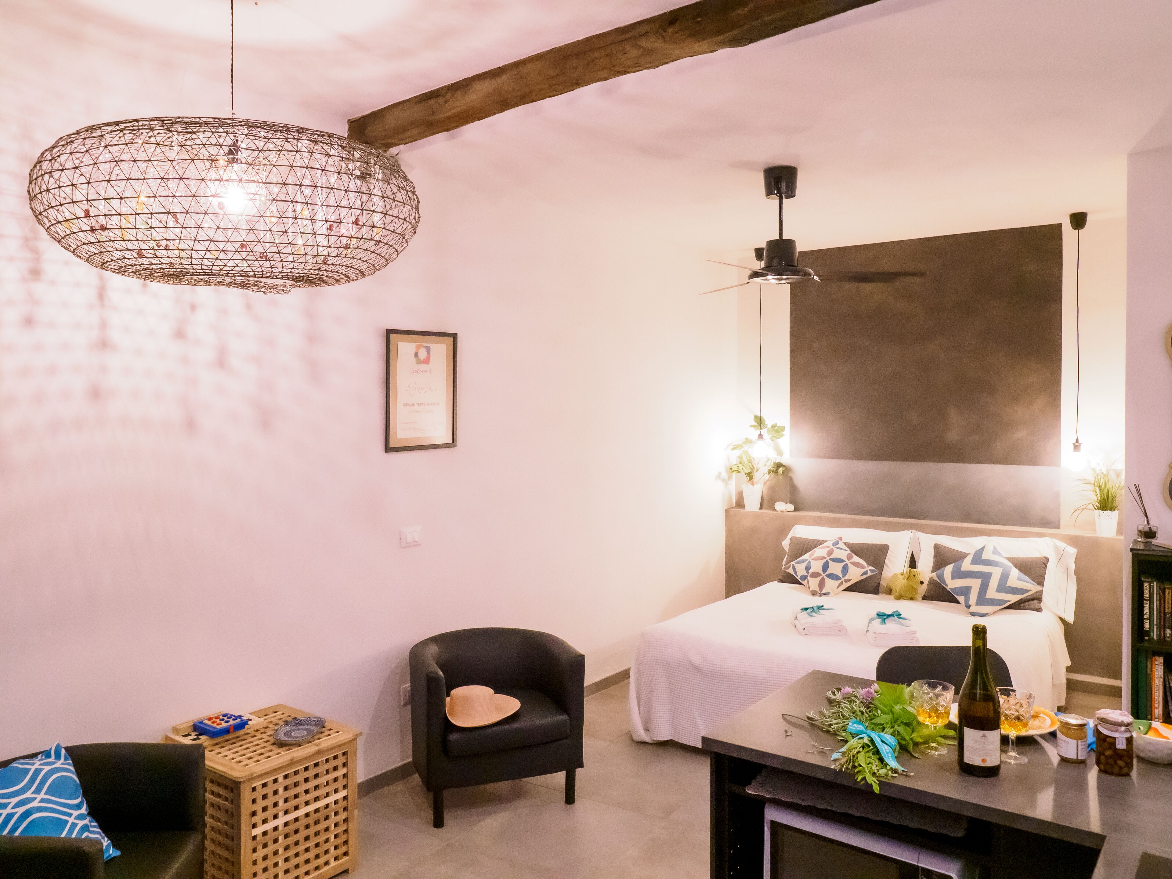 Una camera da letto moderna con un letto, una scrivania, una sedia, una lampada a sospensione e una ventola a soffitto.