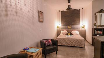 A compact hotel room with a bed, a desk, a chair, and a small table.