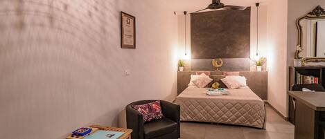 Ein kleines Hotelzimmer mit einem Bett, einem Schreibtisch, einem Stuhl und einem kleinen Tisch.