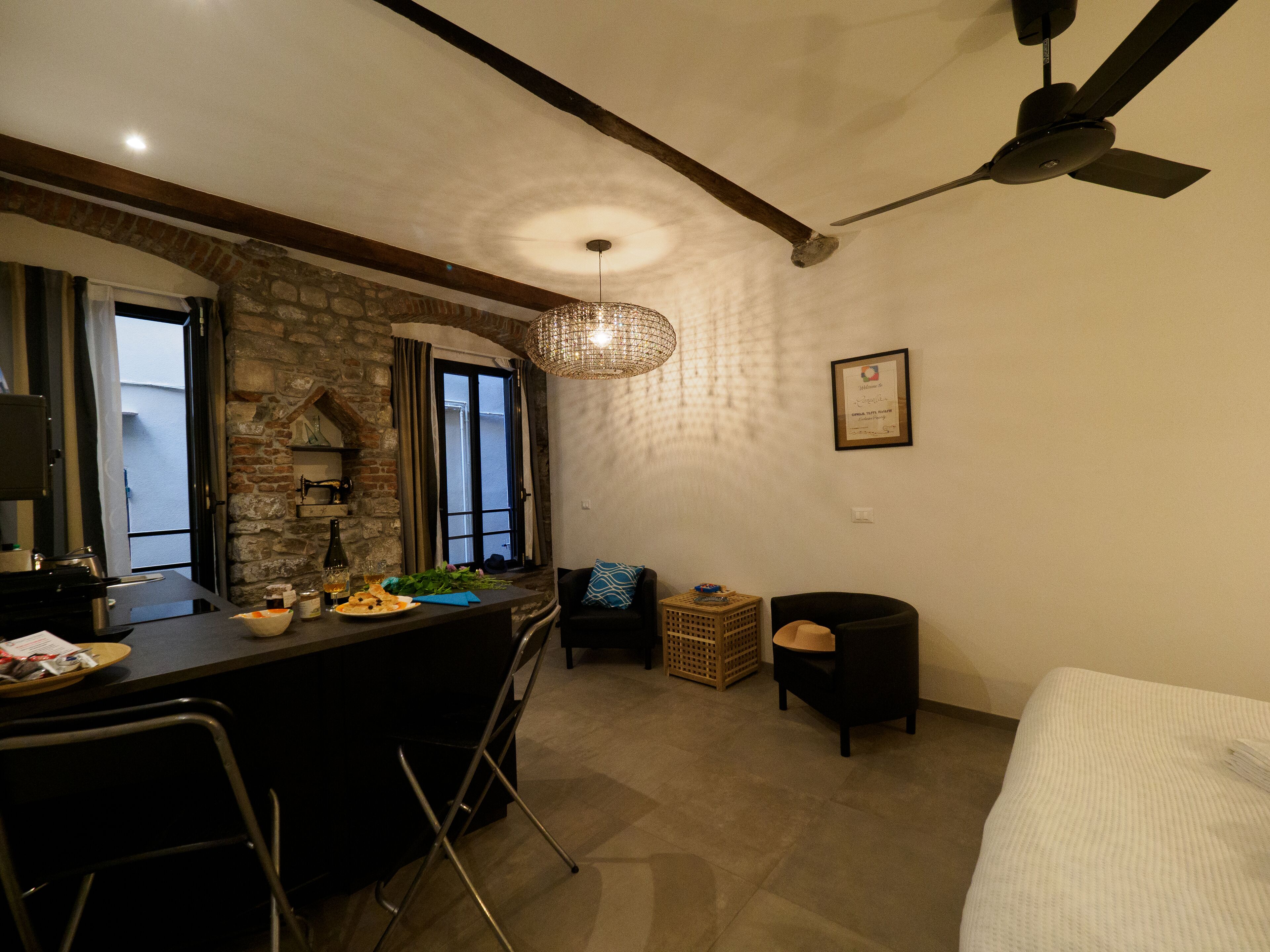 A kitchen with a dining area, a ceiling fan, and a stone wall.