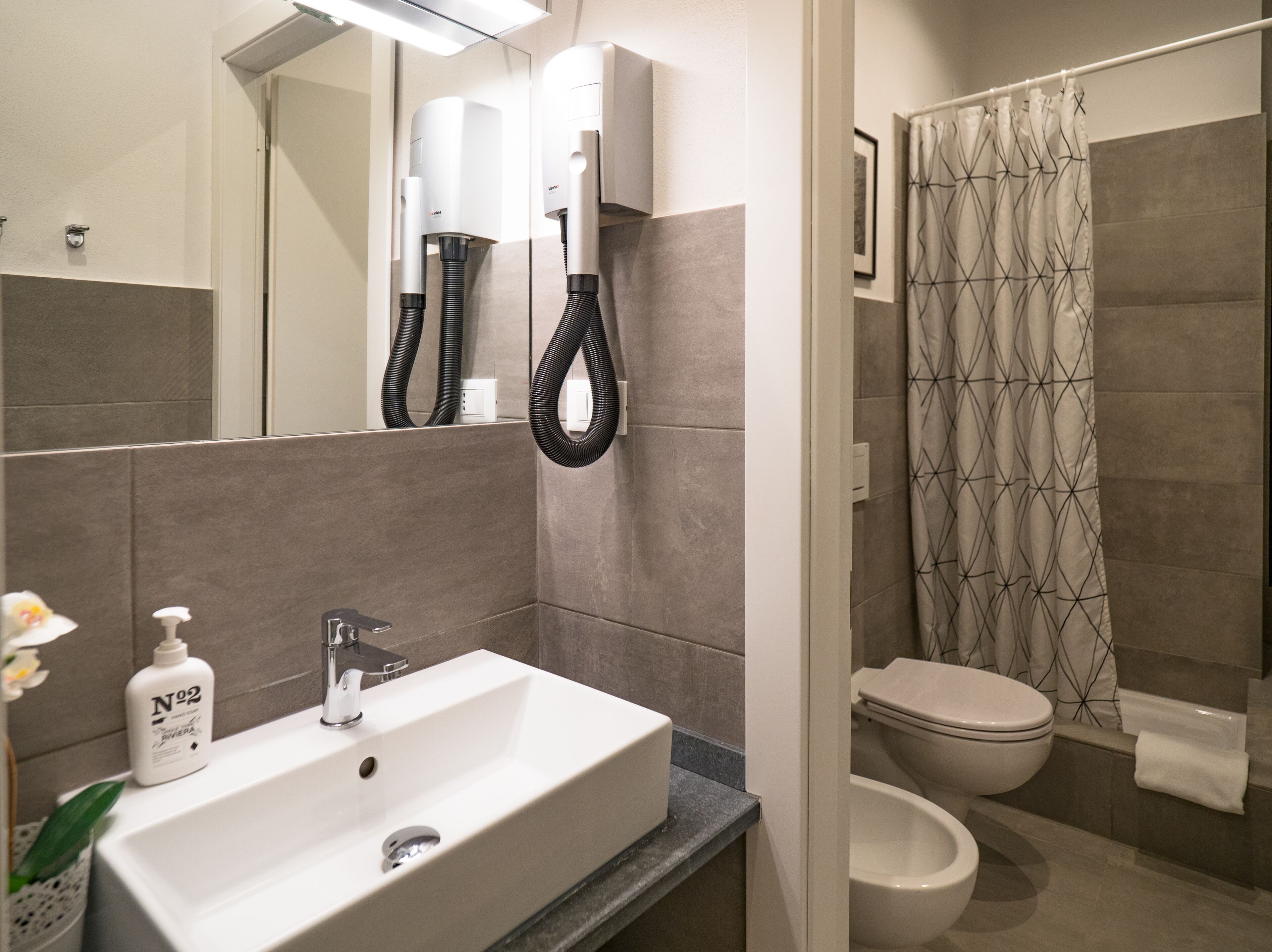 A modern bathroom with a white sink, a toilet, and a shower curtain.